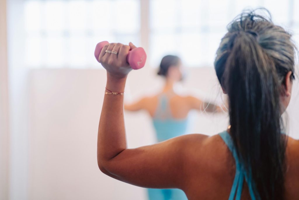 A woman facing away from the camera exercising lifting a weight