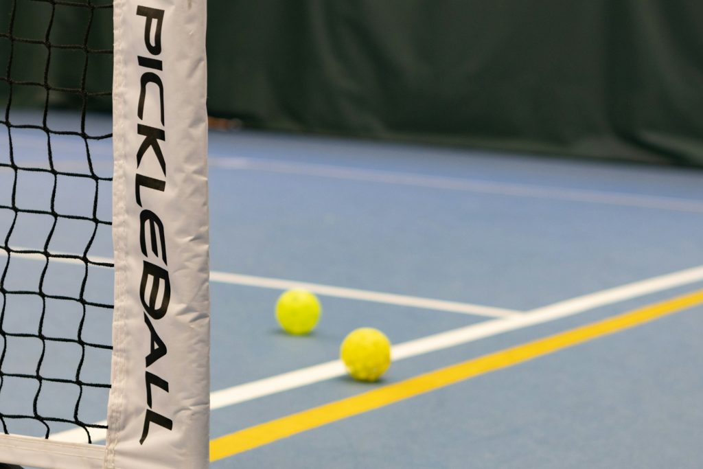 Two pickleballs on a pickleball court