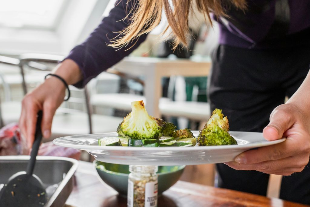 A woman serving vegetables onto a plate