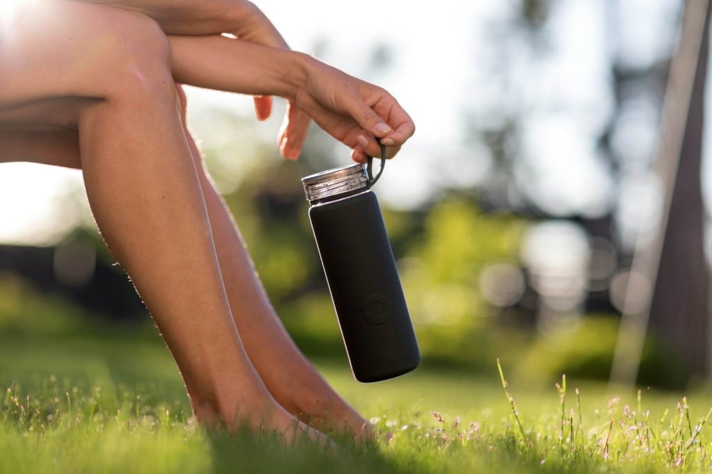 A woman holding a water bottle outside on a summer's day