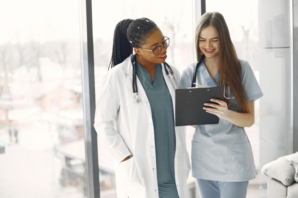 Two female doctors looking at medical notes on a clipboard